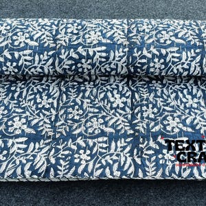 May include: A blue and white kantha quilt with a floral pattern. The quilt is folded in half and the text "TEXTILES CRAFT" is visible in the bottom right corner.
