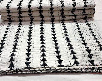 Puede incluir: Una colcha kantha de algodón blanco con patrones de triángulos negros. La colcha está doblada en tres partes y tiene un borde cosido a mano.