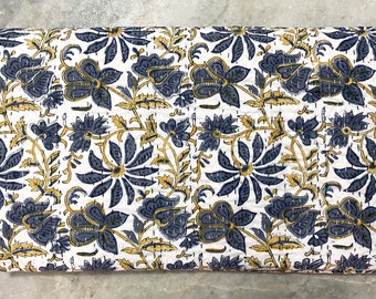 Könnte beinhalten: Eine weiße Baumwolldecke mit einem blauen und gelben Blumenmuster. Die Decke ist in der Hälfte gefaltet und hat einen handgenähten Look.