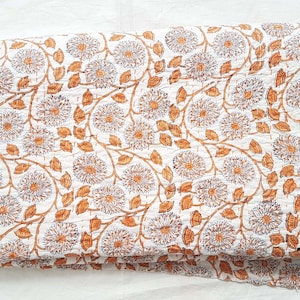 Puede incluir: Colcha de algod&oacute;n blanco con un patr&oacute;n floral en tonos naranja y marr&oacute;n. La colcha est&aacute; doblada en tres partes y tiene una etiqueta "Textiles Craft" en la esquina inferior derecha.