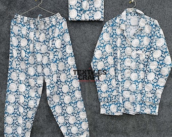 May include: A matching pajama set in teal and white floral print. The set includes a button-down shirt, drawstring pants, and a matching pouch. The fabric is lightweight and appears to be cotton. The pajamas are displayed on hangers against a gray background.