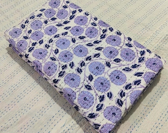 Puede incluir: Una colcha kantha de algodón blanco con un patrón floral en tonos de morado y azul. La colcha está doblada por la mitad y tiene un diseño cosido a mano.