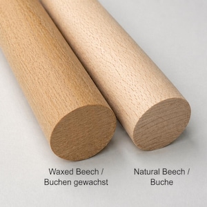 May include: Two wooden dowels, one waxed beech and one natural beech, are displayed side-by-side. The waxed beech dowel is a darker, warmer tone, while the natural beech is lighter. The ends are rounded. Text indicates the wood types.