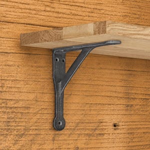 Könnte beinhalten: Ein dunkelgrauer Regalwinkel aus Metall mit einer dreieckigen Stützstruktur und einer flachen Auflageplatte, befestigt an einem hellbraunen Holzregal. Der Winkel verfügt über einen vertikalen Arm mit zwei Schraublöchern oben und einem unten.
