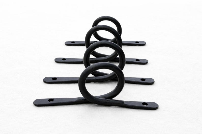 May include: Black metal hardware with a looped design. Each piece has a circular loop connected to a flat, rectangular base with a hole at each end. The hardware is arranged in a row against a white background.