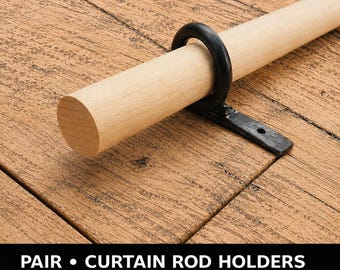 May include: A black metal curtain rod holder featuring a circular ring bracket attached to a flat mounting plate, supporting a light-colored wooden rod. The text at the bottom reads: PAIR • CURTAIN ROD HOLDERS 3 SIZES + CUSTOM • 2 FINISHES.