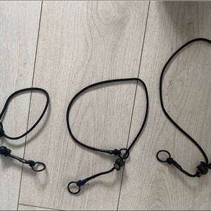 May include: Three black dog leashes of different lengths with metal clasps and black plastic attachments.