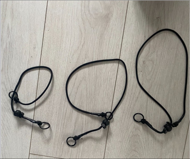 May include: Three black dog leashes of different lengths with metal clasps and black plastic attachments.