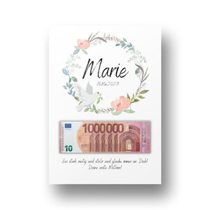 May include: A white card with a floral wreath and a dove holding a leaf. The card has the name "Marie" and the date "16. Mai 2023" written on it. A 10 euro bill is visible with the text "1000000" and "Sei stark, mutig und stolz und glaube immer an Dich! Deine erste Million!"