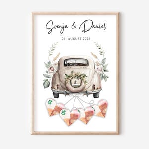 Può includere: Stampa incorniciata con un'auto d'epoca decorata con fiori, i nomi "Svenja & Daniel" e la data "09. AGOSTO 2025" sopra. Sotto, decorazioni a forma di cuore fatte di banconote.
