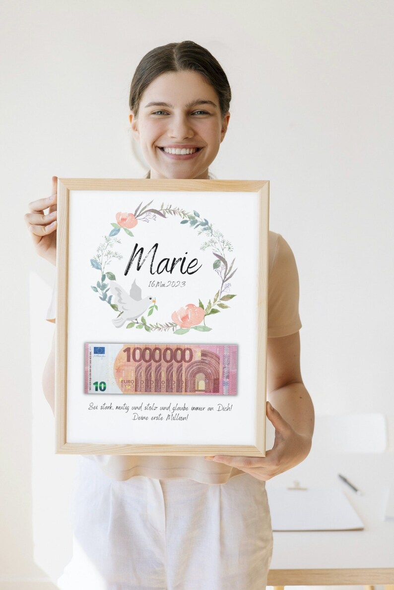 May include: A framed print with a watercolor floral wreath, a dove, and the name "Marie" with the date "16M 2023". A stylized image of a 10 euro bill with the number "1000000" is below the wreath. The text "Sei stark, mutig und stolz und glaube immer an Dich! Deine erste Million!" is below the bill.
