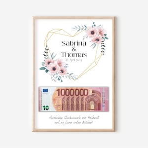 May include: A white card with a gold geometric heart design and pink flowers. The text "Sabrina & Thomas 18. April 2024" is printed on the card. A 10 Euro bill is placed on the card. The text "Herzlichen Gl&uuml;ckwunsch zur Hochzeit und zu Eurer ersten Million!" is printed below the bill.