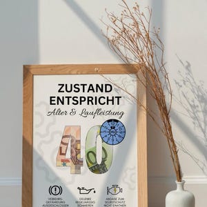 Pode incluir: Uma impress&atilde;o emoldurada com o texto "ZUSTAND ENTSPRICHT Alter & Laufleistung" e o n&uacute;mero "40" feito com dinheiro. A impress&atilde;o inclui &iacute;cones e texto em alem&atilde;o. Um vaso com galhos secos est&aacute; ao lado da moldura.