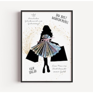 May include: Black framed art print featuring a silhouette of a person holding shopping bags. The person's dress is made of folded money. Text includes "Happy Birthday" and "You are wonderful."