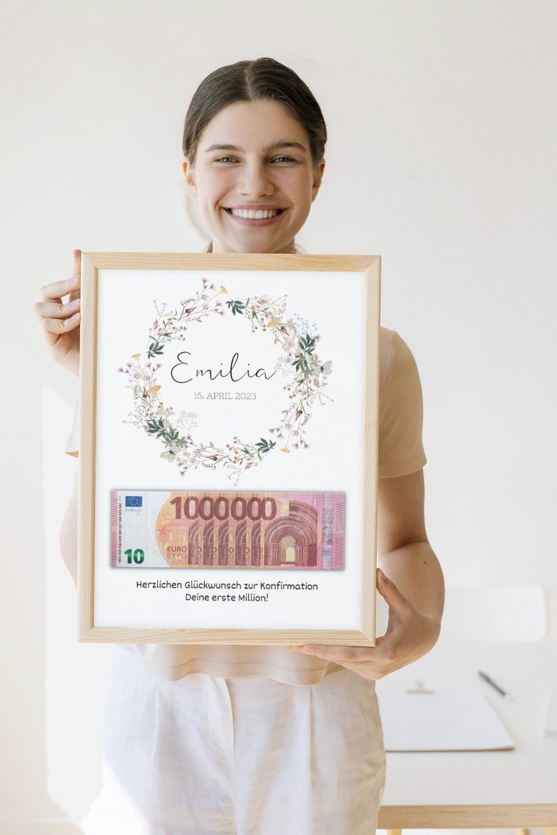 May include: A framed print with a floral wreath design and the name "Emilia" and the date "16. APRIL 2023". A fake 10 euro bill with the number "1000000" is displayed below the wreath. The text "Herzlichen Gl&uuml;ckwunsch zur Konfirmation Deine erste Million!" is printed below the bill.