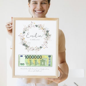 May include: A framed print with a floral wreath and the name "Emilia" and the date "16. APRIL 2023". A mock-up of a 100 euro bill with the number "1000000" is below the wreath. The text "Heraluher Glumbuunsch zur Konfirmation Deine erste Million!" is below the bill.