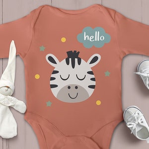 Pode incluir: Um macac&atilde;o de beb&ecirc; cor coral com um gr&aacute;fico de rosto de zebra branco e preto, uma nuvem azul com a palavra "hello" e estrelas amarelas e verdes.