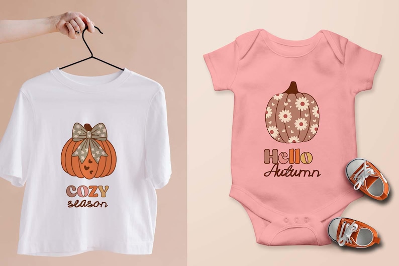 May include: A white t-shirt with an orange pumpkin design and the words "COZY season". A pink baby onesie with a pumpkin design and the words "Hello Autumn". Orange and white baby shoes are next to the onesie.