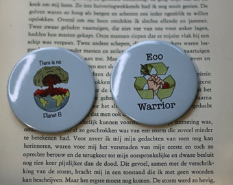 May include: Two round blue and white buttons with a graphic design and text. The first button has a graphic of a tree growing out of a cracked earth with the text "There is no Planet B". The second button has a graphic of a hand holding a branch with a recycling symbol and the text "Eco Warrior".