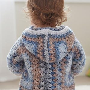 Crochet hooded baby jacket worn by baby, granny square motif body and hood, perfect handmade baby shower gift