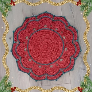 Puede incluir: Un tapete de ganchillo rojo hecho a mano con un borde festoneado y un borde turquesa. El diseño circular presenta un patrón de espiral central y agujeros decorativos. Perfecto para la decoración navideña.