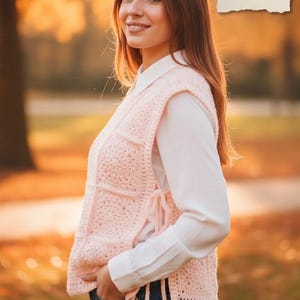 Könnte beinhalten: Eine hellrosa Häkelweste mit quadratischem Muster, getragen über einem weißen Hemd mit Kragen und einer blauen Jeans. Die Weste hat Seitenschlaufen. Text auf einem Papier: Crochet, PDF Pattern, Video Tutorial, Instant Download.