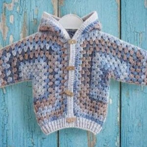 May include: A long-sleeve hooded cardigan featuring a multi-colored granny square crochet pattern in shades of blue, grey, and tan. The garment includes a front button closure with three light-colored wooden toggles and ribbed trim at the cuffs.