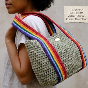 Könnte beinhalten: Eine gehäkelte Tragetasche mit Regenbogenriemen. Die Tasche ist hellgrün und hat ein strukturiertes Aussehen. Der Riemen hat ein lebendiges Regenbogenmuster. Das Bild enthält auch den Text "Crochet, PDF Pattern, Video Tutorial, Instant Download."