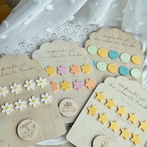 May include: Wooden plaques with various designs, including daisies, smiley faces, stars, and travel-themed illustrations. Each plaque has the German text "Vorfreude ist die sch&ouml;nste Freude" and "Bald ist es soweit."
