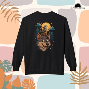 Op de afbeelding: Zwart sweatshirt met een cartoon wolf ontwerp. De afbeelding toont een lachend wolfsgezicht, een huilende wolf, een volle maan, bomen en sterren. De merknaam "SPIKYSTYLES" staat rechtsboven gedrukt.