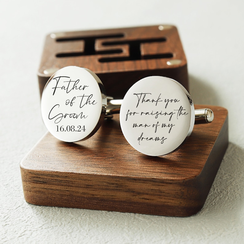 May include: Silver cufflinks with a wooden box. One cufflink says "Father of the Groom 16.08.24" and the other says "Thank you for raising the man of my dreams".