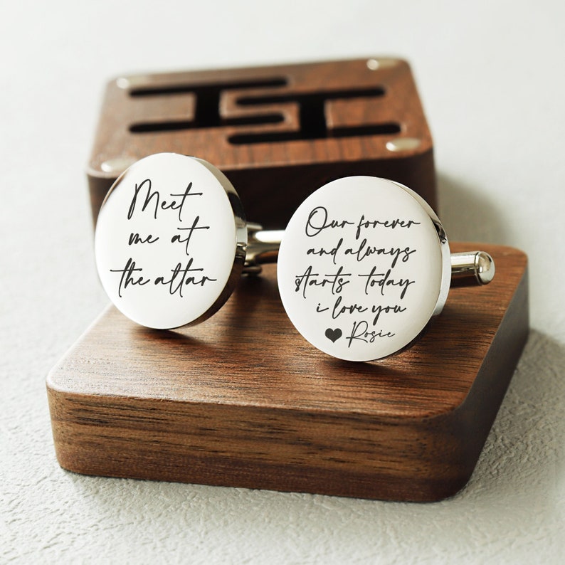May include: A pair of silver cufflinks with engraved messages. One cufflink reads "Meet me at the altar" and the other reads "Our forever and always starts today I love you Rosie" with a small heart symbol.