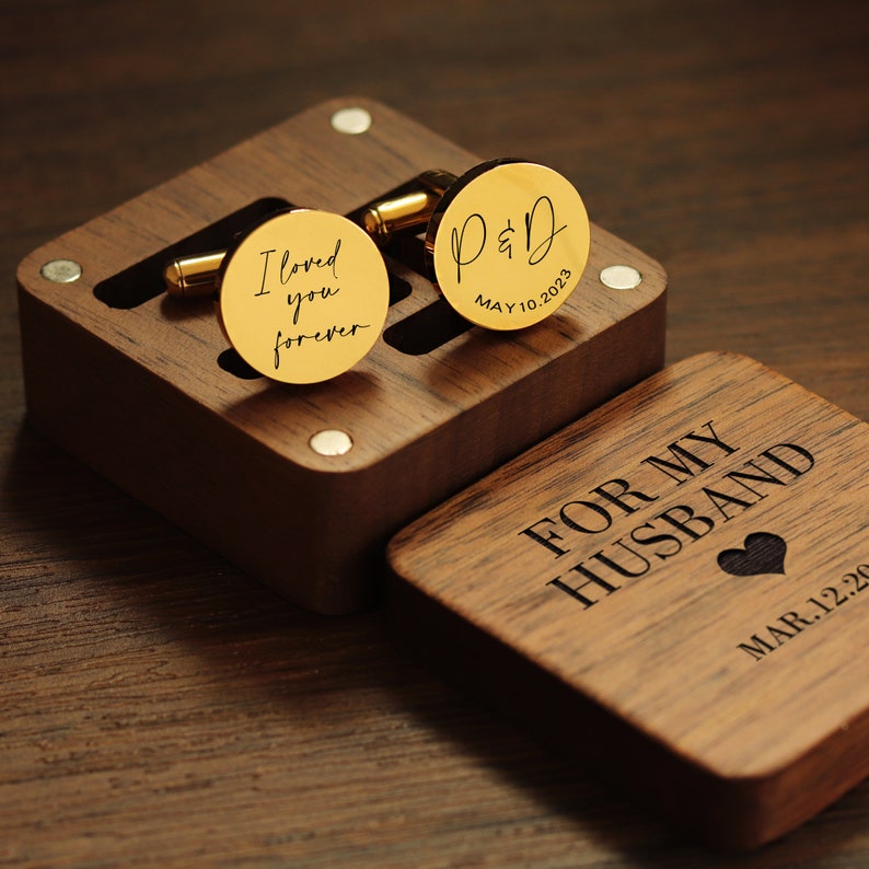 May include: A wooden box with a heart-shaped design and the text "For My Husband" and "Mar 1.2.20". The box contains two gold cufflinks, one with the text "I loved you forever" and the other with the text "P&D May 10.2023".