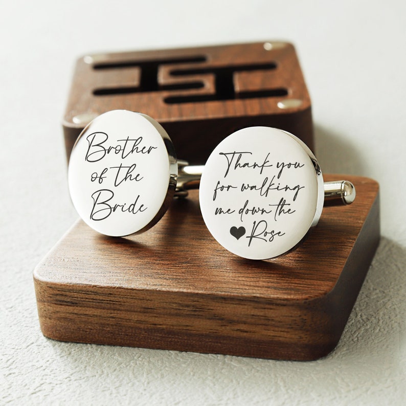 May include: A pair of silver cufflinks with engraved messages. One cufflink says "Brother of the Bride". The other cufflink says "Thank you for walking me down the aisle Rose" with a small heart symbol.