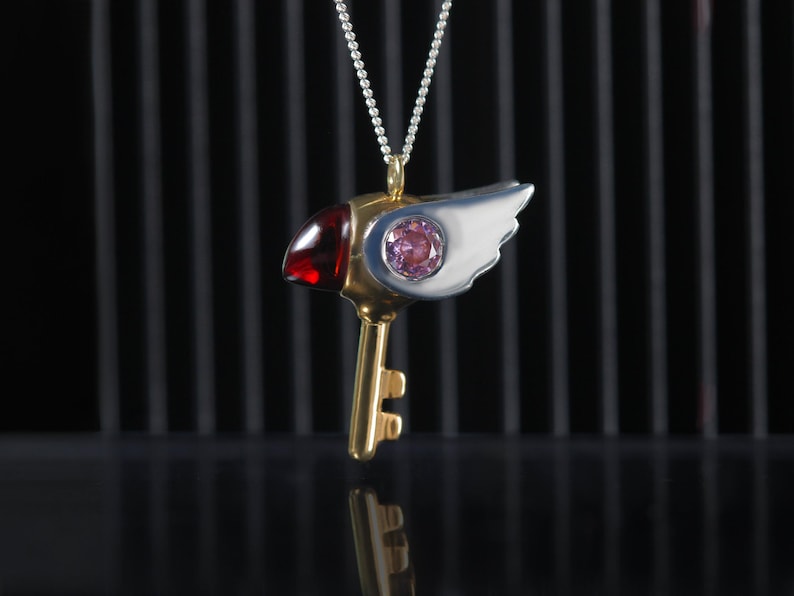 Colgante en plata de ley con forma de pico, circonitas rosa en los ojos yun granate natural como el pico del pájaro.