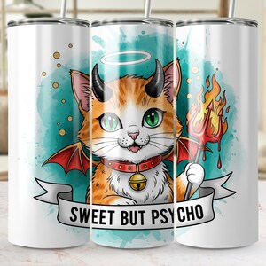 Puede incluir: Un vaso blanco con un gato de dibujos animados con pelaje naranja y blanco, ojos verdes y cuernos de diablo. El gato tiene un halo y alas de murciélago rojas, sosteniendo un tridente en llamas. El texto "SWEET BUT PSYCHO" está en una pancarta.