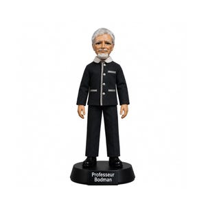 Puede incluir: Una figura cabezona de una persona mayor con pelo gris y barba, que lleva una chaqueta gris oscuro con cuello claro y pantalones a juego. La figura se apoya sobre una base circular negra con el texto Professeur Bodman impreso en blanco.