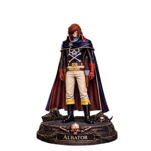 Peut inclure: Figurine détaillée d'un personnage vêtu d'un manteau bleu foncé et noir avec une cape rouge, un pantalon blanc et des bottes noires. La figurine a des cheveux bruns et des gants rouges, et se tient sur une base avec le nom "ALBATOR".