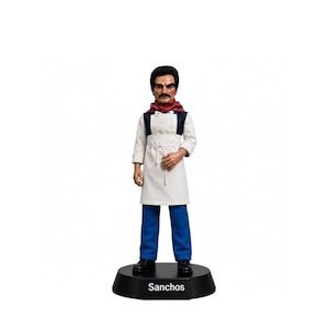 Puede incluir: Una figura de acción masculina con cabello oscuro y bigote, que viste un delantal blanco sobre una camisa blanca, un pañuelo rojo y pantalones azules. La figura se apoya en una base negra con el texto Sanchos impreso en blanco al frente.