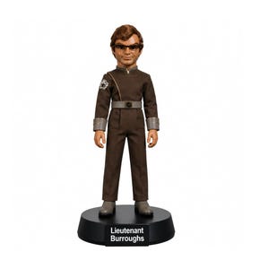 Può includere: Una statuetta da collezione del Tenente Burroughs con capelli castani, occhiali e un'uniforme marrone con cintura e polsini grigi. La figura poggia su una base circolare nera con la scritta Lieutenant Burroughs stampata in bianco sul davanti.