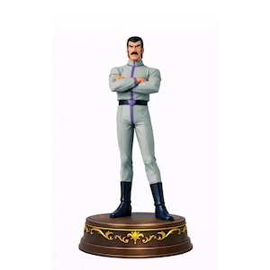 Peut inclure: Figurine d'un homme en uniforme gris avec des détails violets, des bottes noires et une moustache foncée. La figurine est posée sur une base marron avec des détails dorés. L'homme a les bras croisés.