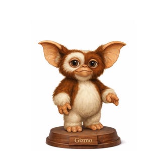 Peut inclure: Figurine détaillée de Gizmo du film Gremlins. La figurine a de grands yeux bruns, une fourrure marron et blanche, et de grandes oreilles. Elle est posée sur un socle en bois avec le nom "Gizmo" gravé.