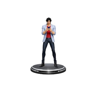 May include: A figurine of a person in a light blue blazer, red shirt, and dark blue pants, holding a smartphone. The figure stands on a circular black base with silver trim. The person is looking at the phone.