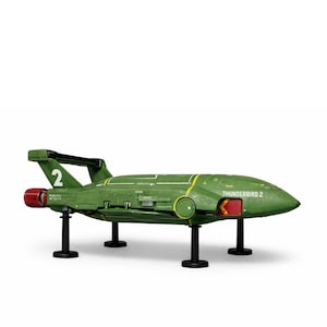 Puede incluir: Un modelo verde del avión Thunderbird 2, con el número 2 en la aleta trasera. El modelo tiene detalles de motor rojos y detalles amarillos. Las palabras "Thunderbird 2" están impresas en el lateral.
