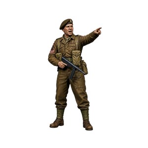 Puede incluir: Una figura a escala detallada de un soldado con uniforme marrón, boina y botas de combate. La figura sostiene un subfusil en una mano mientras señala hacia adelante con la otra, mostrando texturas de tela realistas, bolsillos e insignias.