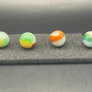May include: Four colorful marbles with swirling patterns. One marble has red, green, and yellow hues. Another features green, yellow, and orange. The third marble is orange and white, and the last one has green, blue, and red. Each marble is a sphere.