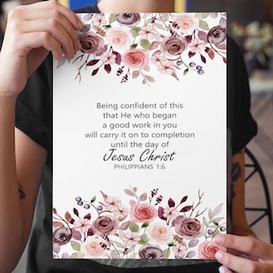 Könnte beinhalten: Ein weißer Druck mit dem Text "Being confident of this that He who began a good work in you will carry it on to completion until the day of Jesus Christ PHILIPPIANS 1:6". Verziert mit Aquarell-Blumenarrangements in Rosa, Lila und Grün.