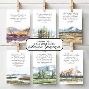 Puede incluir: Seis tarjetas rectangulares con pinturas de paisajes en acuarela y versículos bíblicos impresos, colgadas de una cuerda con pinzas de madera. El texto dice 30 PRINTABLE BIBLE VERSE CARDS Watercolor Landscapes y varios pasajes bíblicos.