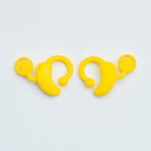 May include: Two yellow plastic ear hooks for a hearing aid. The hooks have a small loop on one end and a larger loop on the other end.