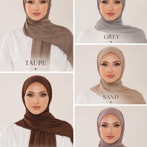 May include: A collection of five hijabs in various neutral colours including taupe, grey, sand, chocolate, and cashmere. Each hijab is draped around the head and neck, featuring smooth fabric textures and labels identifying each specific colour shade.